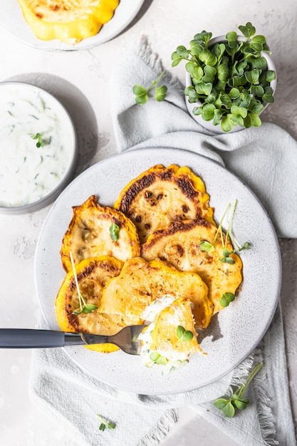 Gebratene Patisson oder gelbe Zucchini mit Sauce und Mikrogrün, grauer Betonhintergrund. Ansicht von oben.