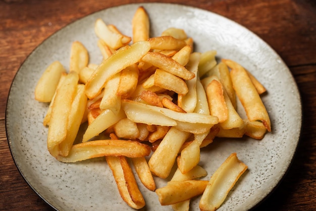 Gebratene Pommes frites in Keilen auf einem Teller auf Holzhintergrund