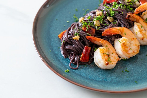 Gebratene schwarze Spaghetti mit Knoblauch und Garnelen auf dem Teller