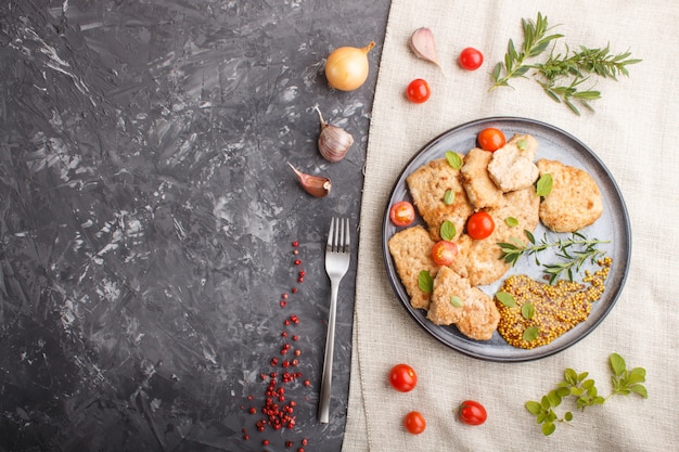 Gebratene Schweinekoteletts mit Tomaten und Kräutern auf einer grauen keramischen Platte. Draufsicht, copyspace.