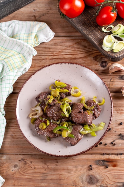 Gebratene Schweinemedaillons mit Lauch und Gewürzen auf Draufsicht des Holztischs