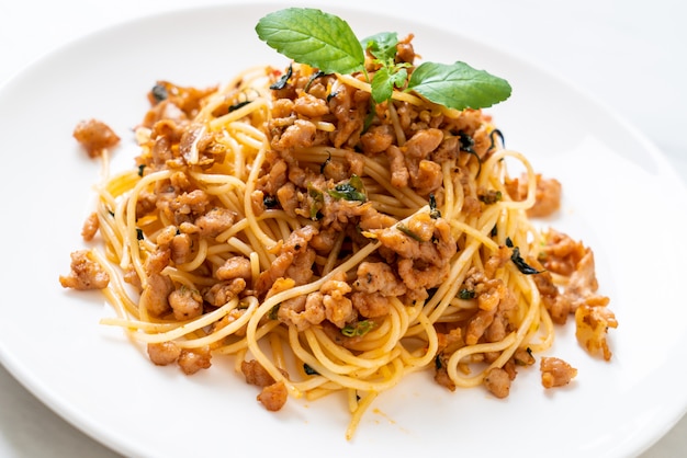 Gebratene Spaghetti mit gehacktem Schweinefleisch und Basilikum verrühren