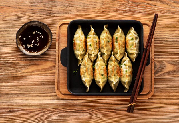 Gebratene Teigtaschen Gyoza in einer Pfanne, Sojasauce und Stäbchen ÃƒÂ Ã'Â½ÃƒÂ Ã'Â° Holzhintergrund, Ansicht von oben