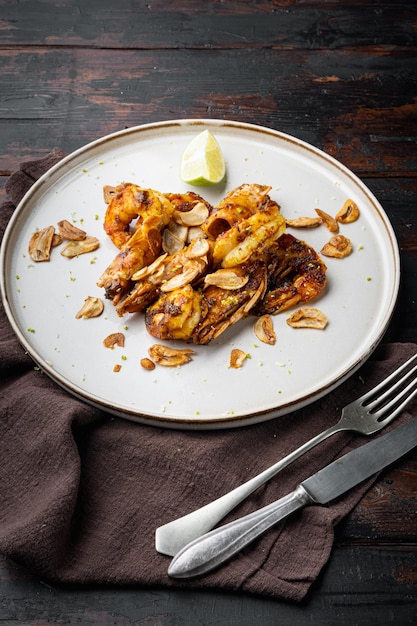 Gebratene Tigergarnelen mit Mango-Chutney und knusprigem Knoblauch-Set, auf Teller, auf altem dunklem Holztischhintergrund