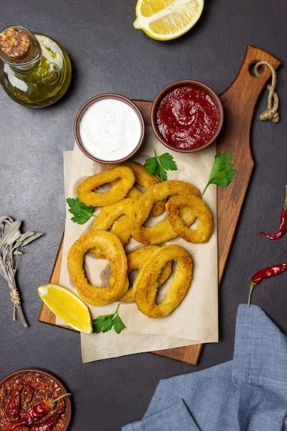 Gebratene Tintenfischringe mit zwei Saucen, Zitrone und Kräutern. Fastfood. Vorspeise.