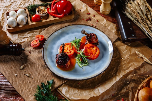 Gebratene Wachtelbeine mit Tomaten auf einer Draufsicht der Platte