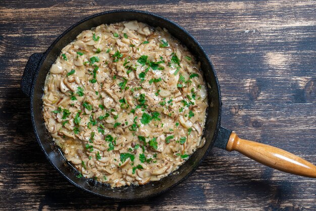 Gebratene Wildpilze auf der Pfanne. Gebraten von Steinpilzen in der Pfanne auf einem hölzernen Hintergrund, nah oben. Ukraine