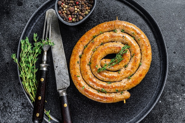 Gebratene würzige spiralförmige Fleischwurst auf einem Teller.