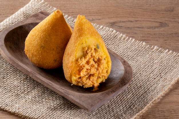 Gebratener Coxinha in Holzbehälter auf Holztisch.