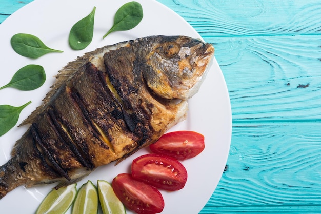 Gebratener Fisch Dorado mit Limettentomaten und Spinat. Meeresfrüchte-Hintergrund