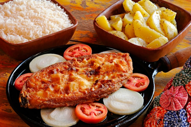Foto gebratener fisch im steak mit zwiebeln und tomaten mit reis und kartoffeln gericht aus dem brasilianischen nordosten