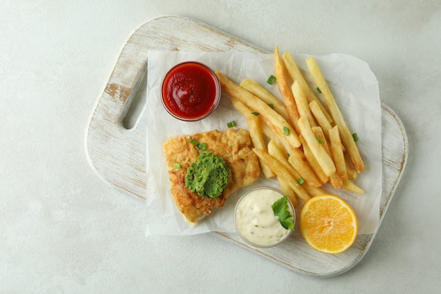 gebratener Fisch und Chips auf weißem strukturiertem Hintergrund