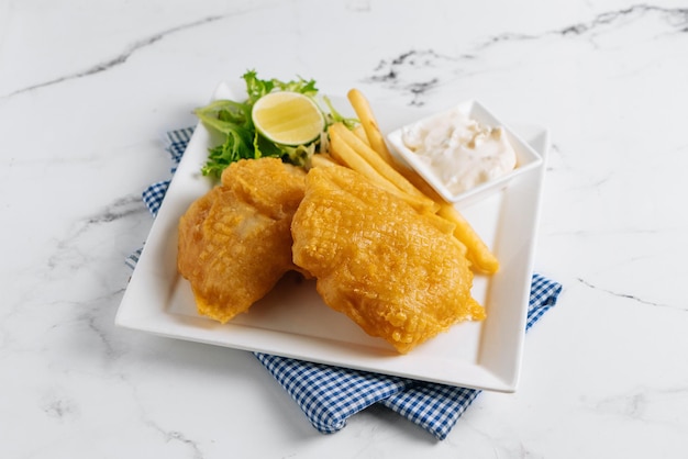 Gebratener Fish and Chips mit Limette in einem Geschirrkorb isoliert auf Serviettenseitenansicht auf grauem Hintergrund berühmtes indisches und pakistanisches Essen