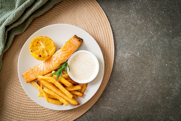 Gebratener Lachs Fish and Chips mit Zitrone auf dem Teller