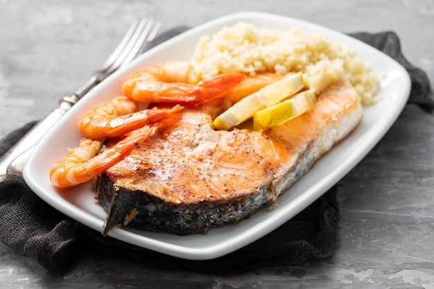 Gebratener Lachs mit Garnelen und Couscous auf weißem Teller