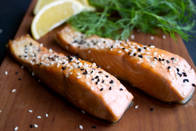 Gebratener Lachs mit indischem Sesam, Zitrone, Dill auf einem Holzbrett. Selektiver Fokus