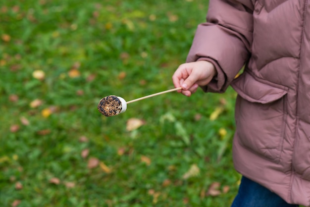 Gebratener Marshmallow auf einem Stock in der Hand eines Kindes