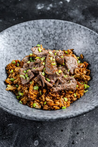 Gebratener Reis des chinesischen Wok mit Gemüse und Rindfleisch. Schwarzer Hintergrund.