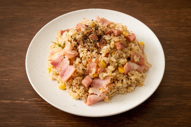 Gebratener reis mit speckschinken und schwarzer paprika auf weißem teller