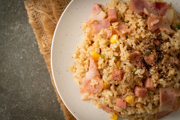 gebratener Reis mit Speckschinken und schwarzer Paprika auf weißem Teller