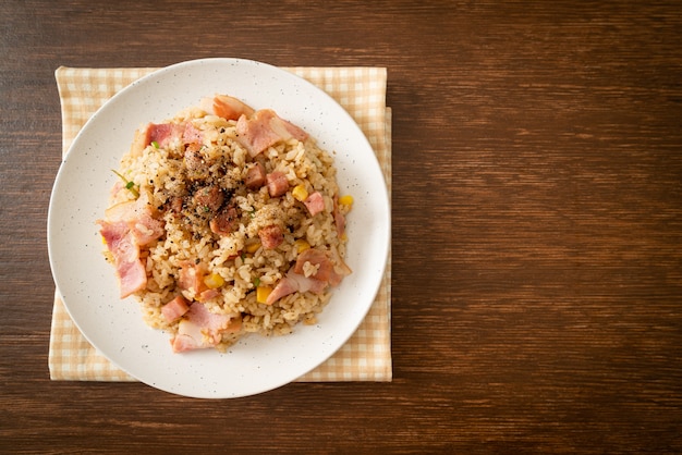 gebratener Reis mit Speckschinken und schwarzer Paprika auf weißem Teller