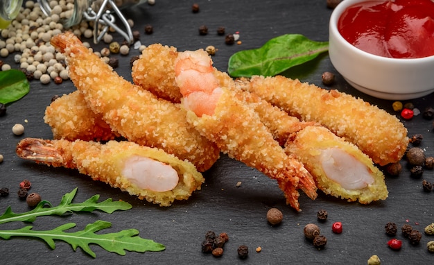 Gebratener Shrimps Tempura mit süßer Chilisauce auf einem schwarzen Steinbrett