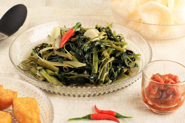 Gebratener Wasserspinat (Tumis Kangkung) ist eines der indonesischen Tagesmenüs und Lieblingsessen, ganz nah auf dem Tisch. Serviert mit gebratenem Tofu und Shrimp Cracker