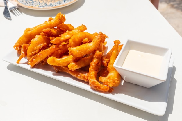 Gebratener zerschlagener Tintenfisch mit Mayonnaise-Sauce Traditionelle mediterrane Küche auf einem weißen Tisch