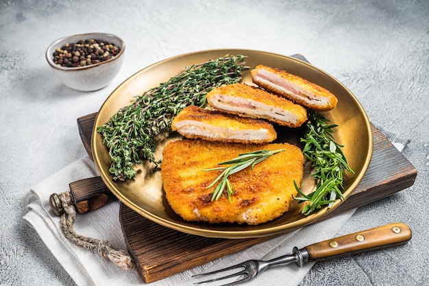 Gebratenes Cordon Bleu Hähnchenschnitzel mit Schinken und Käse auf einem Teller mit Kräutern Weißer Hintergrund Ansicht von oben