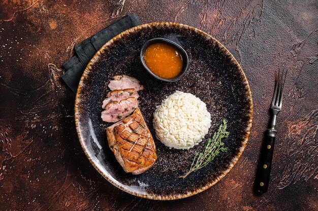 Gebratenes Entenbruststeak, Geflügelfiletfleisch mit Sauce und Reis. Dunkler Hintergrund. Ansicht von oben.