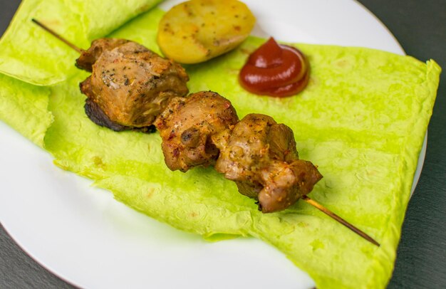 Gebratenes Fleisch auf grünem Fladenbrot mit Spinat und Erbsen und Ofenkartoffeln