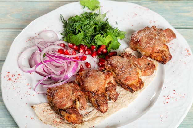 Gebratenes Fleisch. Kebab mit Zwiebeln, Grüns und Granatapfel