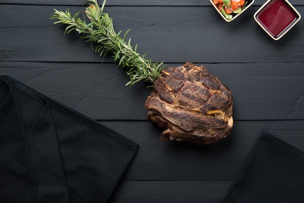 Gebratenes Fleisch mit Gemüse, Sauce und Soße auf schwarzem Holzhintergrund