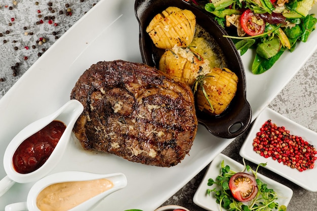 Gebratenes Fleischsteak mit Bratkartoffeln, Champignons, Tomatensauce und Kräutern