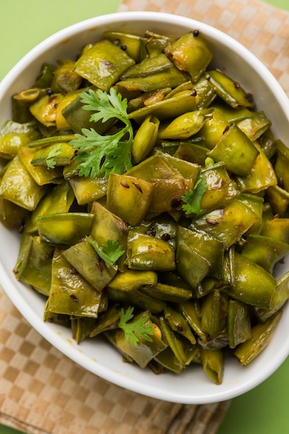 Gebratenes Gemüsegericht namens Flat Green Beans mit Gewürzen, serviert in einer Keramikschale, über stimmungsvollem Hintergrund. selektiver Fokus