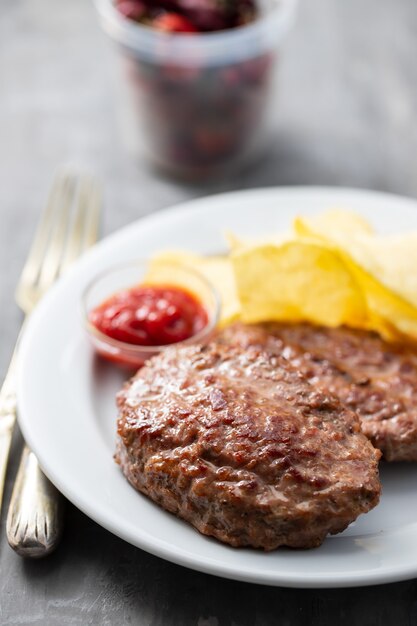 Gebratenes Hackfleisch mit Tomatensauce und Kartoffelchips auf Teller