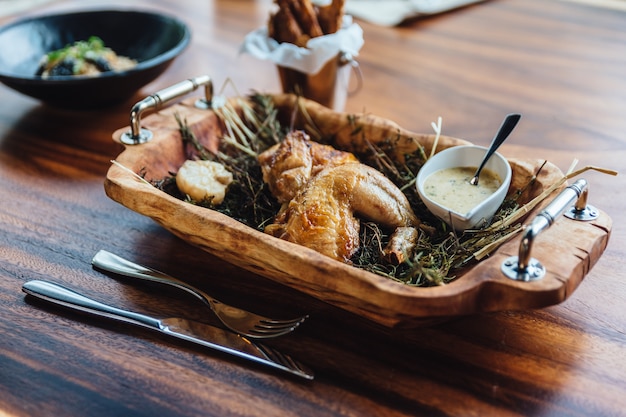 Gebratenes Huhn mit Kräutern, Rosmarin und Knoblauch im hölzernen Behälter diente mit weißer Soße.