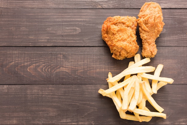 Gebratenes Huhn und Pommes-Frites auf einem hölzernen Hintergrund