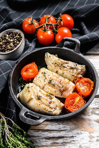 Gebratenes Kabeljaufilet mit Gewürzen in einer gusseisernen Pfanne. Weißer Hintergrund. Draufsicht.