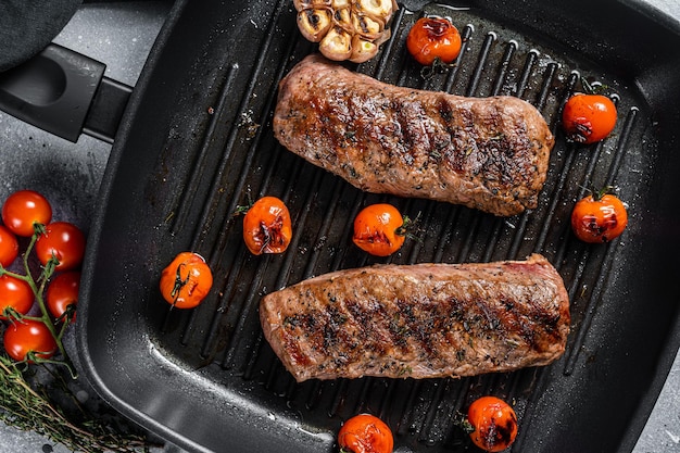 Gebratenes Lammfiletfilet auf Grillpfanne, Hammelfiletsteak. Grauer Hintergrund. Ansicht von oben.