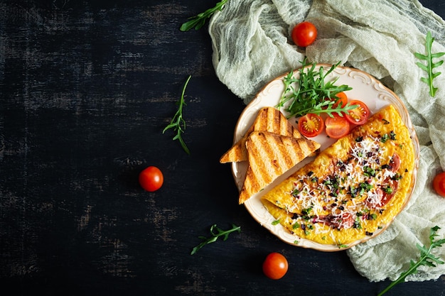 Gebratenes Omelett, gefüllt mit Wurst, Tomaten, Grün und Käse Leckeres einfaches Frühstück Draufsicht