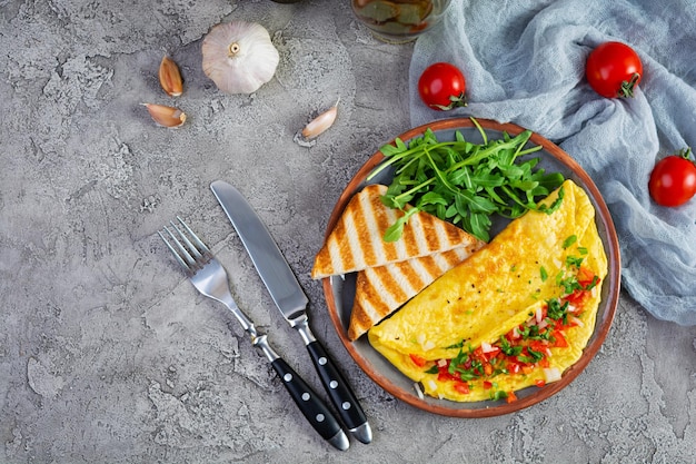 Gebratenes Omelett mit Tomaten, Zwiebeln und Kräutern. Leckeres Frühstück mit Eiern und Toast. Ansicht von oben