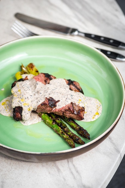 Gebratenes Rib-Eye-Steak mit grünem Spargel auf altem Blatt