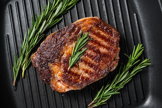 Gebratenes Rib-Eye-Steak Ribeye-Rindfleisch in einer Grillpfanne Draufsicht auf schwarzen Hintergrund