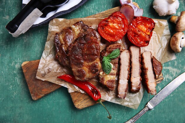 Gebratenes Rinderfilet und Gemüse auf Schneidebrett auf Holzhintergrund