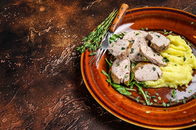 Gebratenes Schweinefiletsteak auf einem Teller mit Kartoffelpüree. Dunkler Hintergrund.