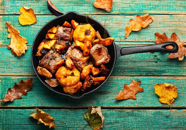 Gebratenes Schweinefleisch mit Herbstquitte in einer Eisengusspfanne.Gedünstetes Fleisch