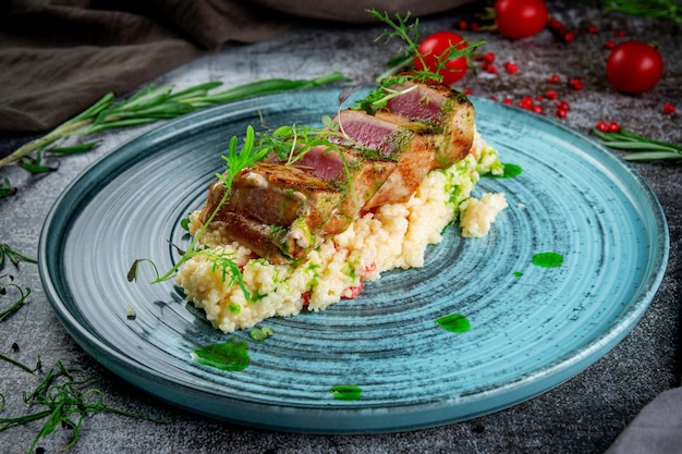 Gebratenes Thunfischfilet mit Couscous und Kräutern auf einem grauen Steintisch xA