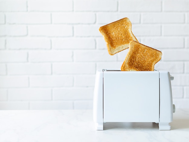 Foto gebratenes toastbrot aus toaster mit weißer mauer.