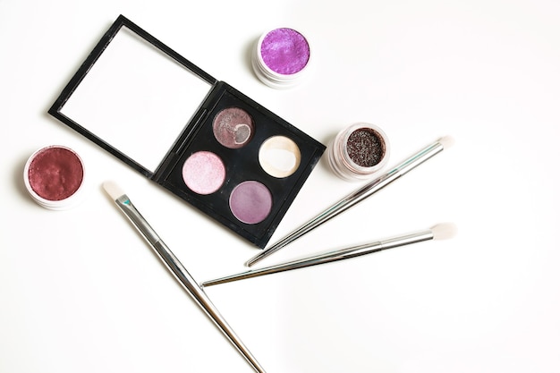 Gebrauchte Make-up-Palette, Pigment, Creme-Lidschatten und professionelle Pinsel auf weißem Hintergrund
